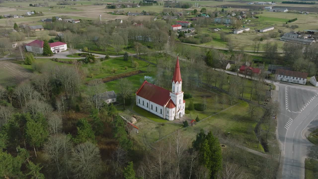 vista aérea de una iglesia blanca con techo rojo en un soleado día de primavera, disparo de órbita de drone de ángulo ancho distante