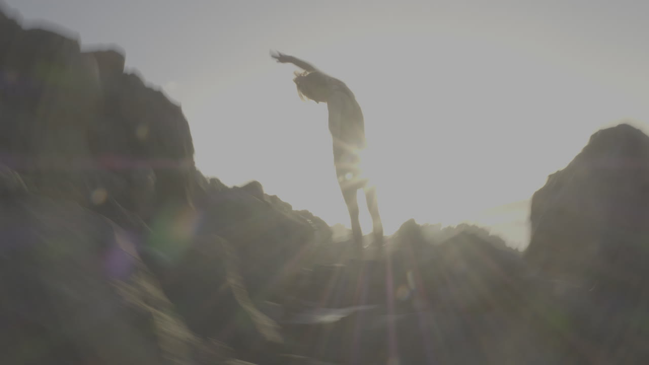 Woman jumping on rocks at sunrise