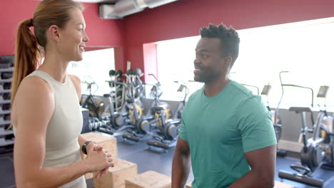 Fit-Junge-Kaukasische-Frau-Und-Afroamerikanischer-Mann-Posieren-In-Einem-Fitnessstudio