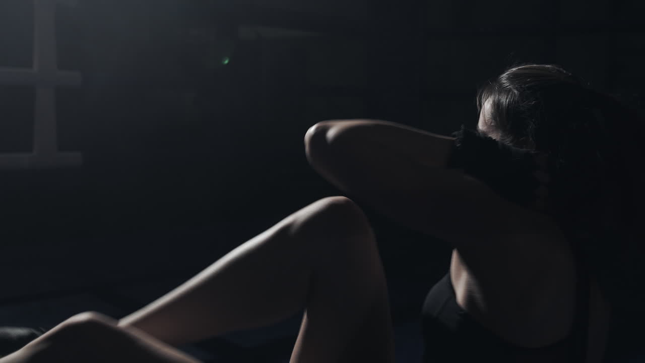 Donna che fa sit-up in una palestra scura
