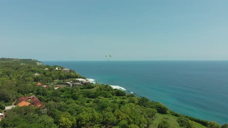 Paraglider-above-tropical-lush-shore-of-Bali-island-with-blue-ocean