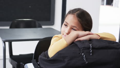 In-a-school-setting,-a-young-Caucasian-student-rests-her-head-on-her-arms