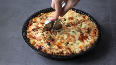 cortando una deliciosa pizza de pasta al horno