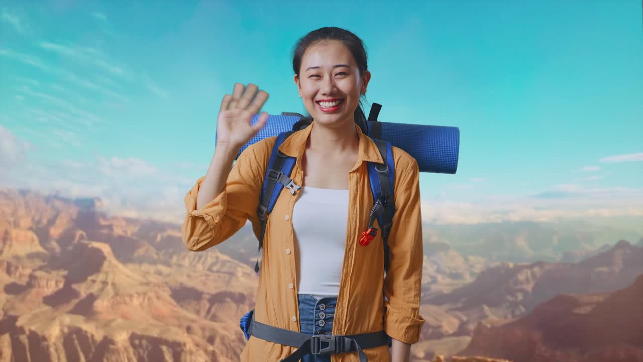 Asian Female Hiker With Mountaineering Backpack Waving Hand And Saying Bye While Traveling At The Top Of Mountain