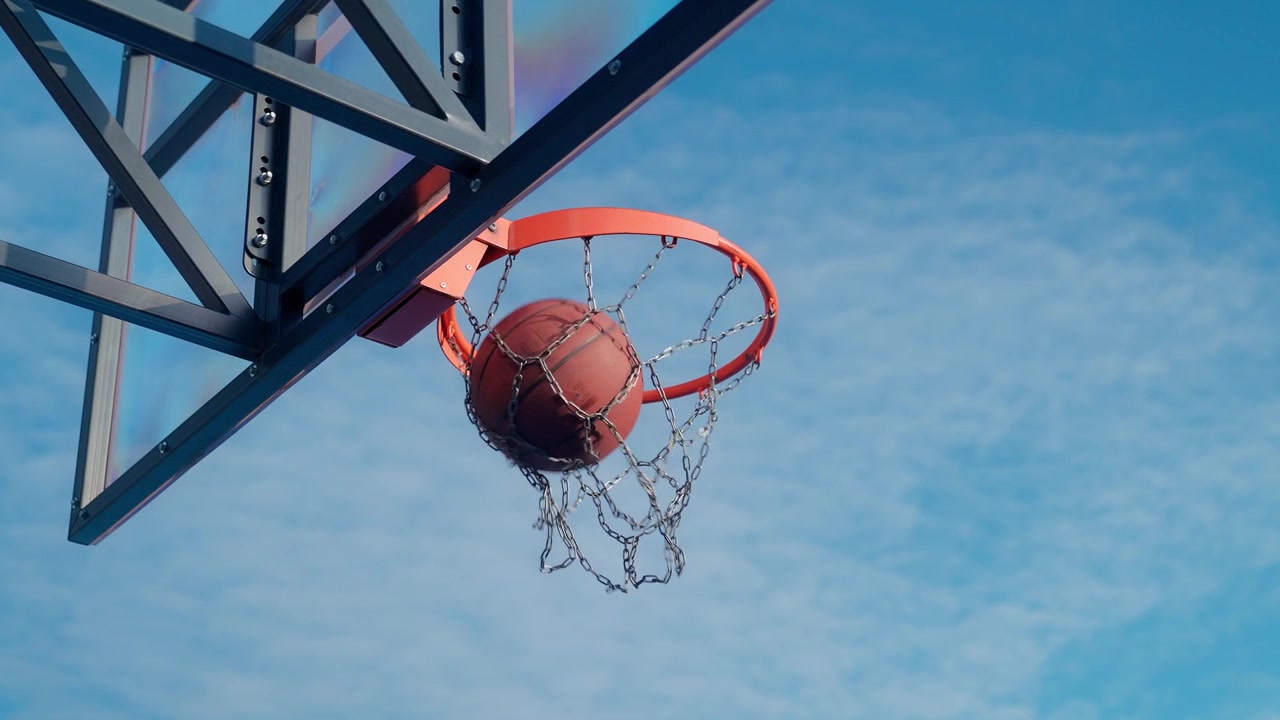 Pallone da basket che entra nel canestro contro un cielo blu