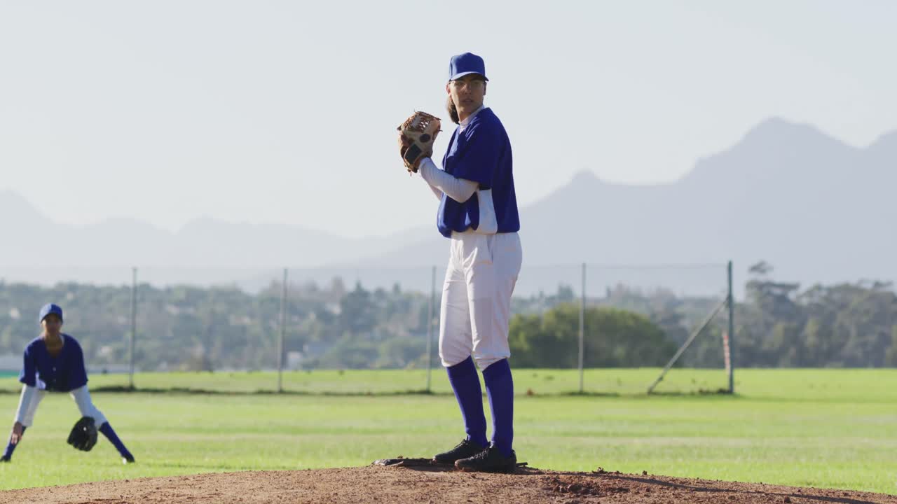 Giocatrice di baseball caucasica con gli occhiali che lancia la palla su un campo da baseball.