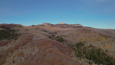 Flying-Over-Hills-In-Fall-Foliage-Against-Clear-Blue-Sky-In-Utah,-USA