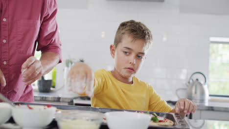 Feliz-Abuelo-Caucásico-Y-Nieto-Haciendo-Pizza-En-La-Cocina,-Cámara-Lenta