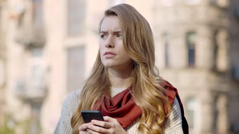 Upset-woman-using-phone-outside.-Stressed-girl-looking-around-on-city-street