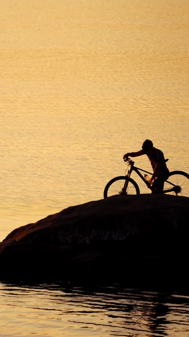 Sportive man with bicycle at sunset. Man with a bike enjoys the view of sunset Vertical video