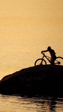 sportive man with bicycle at sunset. man with a bike enjoys the view of sunset vertical video
