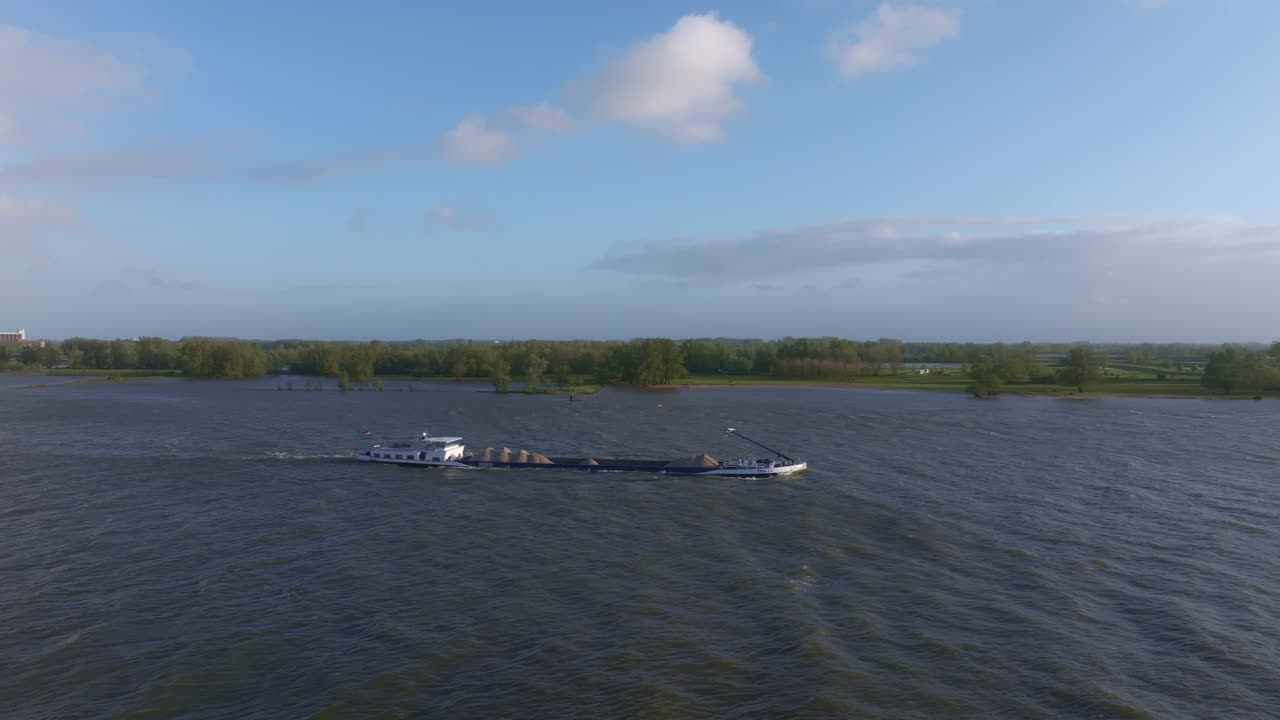 Gylden solnedgang over et fragtskib, der glider på Waal-floden i Gorinchem, Holland
