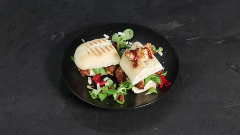 a sandwich bread with paprika, salad and meat is presented on a spinning plate