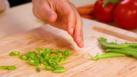 hands slicing green peas with tomatoes nearby