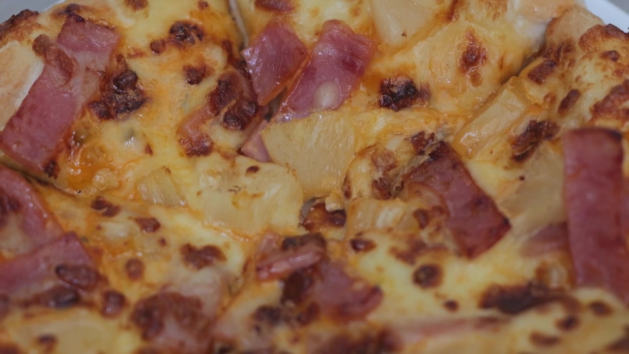 Primo piano di pizza al prosciutto e formaggio appena sfornata, guarnita con formaggio dorato fuso, prosciutto saporito e una crosta dorata e croccante