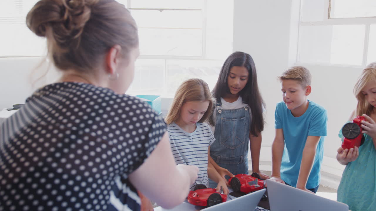 profesor hablando con un grupo de estudiantes en la clase de computadora después de la escuela aprendiendo a codificar