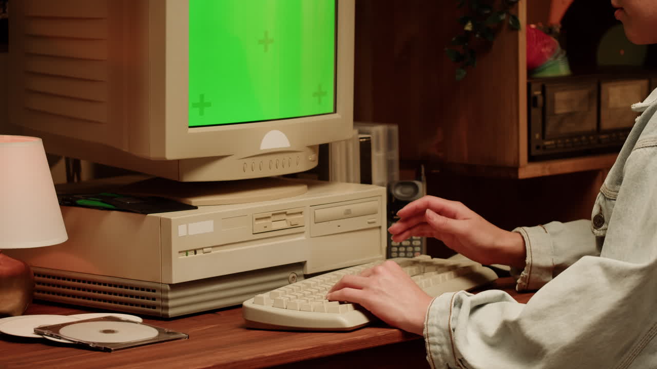Person using vintage computer with green screen monitor