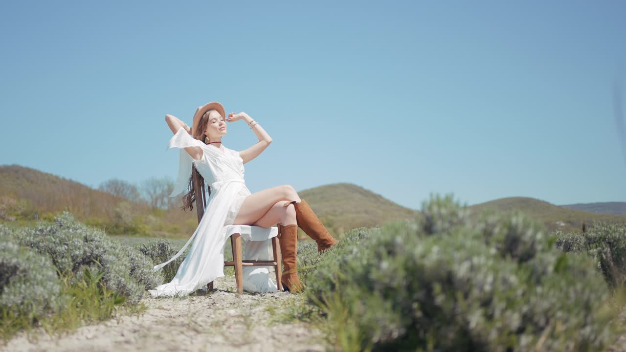 색 드레스,  모자, 갈색 부츠 를 입은 여자 가 라벤더  에 앉아 있다