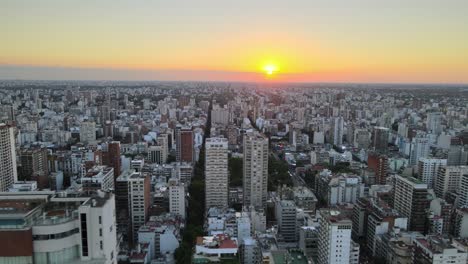 aerial track right of belgrano neighborhood buildings and skyscrapers at sunset with bright sun in background, buenos aires, argentina