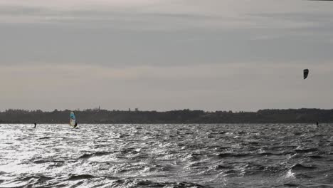 Vista-Escénica-De-Kiteboarders-En-El-Mar-Báltico-En-Rewa,-Polonia-Bajo-El-Cielo-Dramático---Amplia-Toma-En-Cámara-Lenta