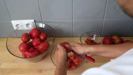 cierre de manos masculinas cortando tomates en trozos pequeños antes de agregarlos a la blenda para hacer salsa de tomate casera