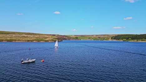 winscar reservoir in yorkshire serves as the backdrop for a weekend sporting event, where sailing enthusiasts indulge in a thrilling boat race with their small one-man boats