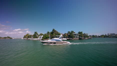 yacht cruising slowly in miami with some nice houses in the background