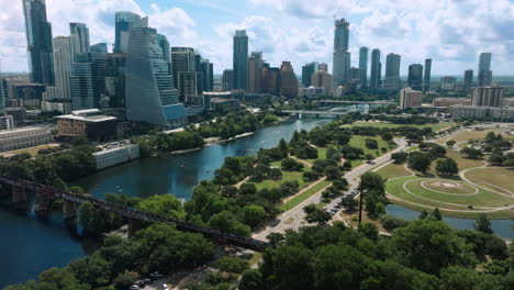 daytime drone shot captures auditorium shores, lady bird lake, and the full austin skyline on a beautiful blue-sky day. clear air, bright light, and vibrant colors of scenic city view
