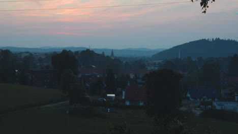 panning shot of european town at dusk with rolling hills and town rooftops. kowary, poland