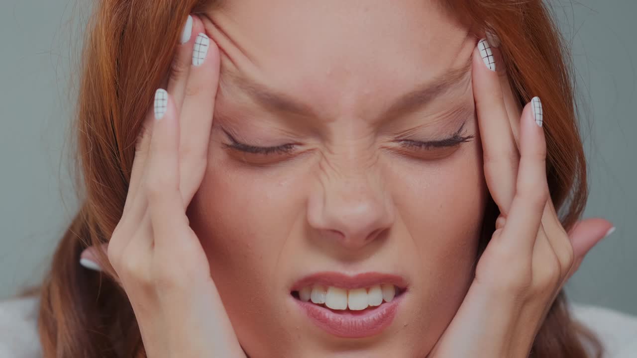 피곤한 백인 여성은 깊게 숨을 들이마시며 신문을 마사지하여 긴장을 풀어줍니다.