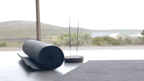 rolled yoga mat and incense sticks on floor, creating peaceful home atmosphere