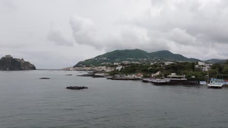 low forward aerial of houses and restaurants by shore at ischia, italy