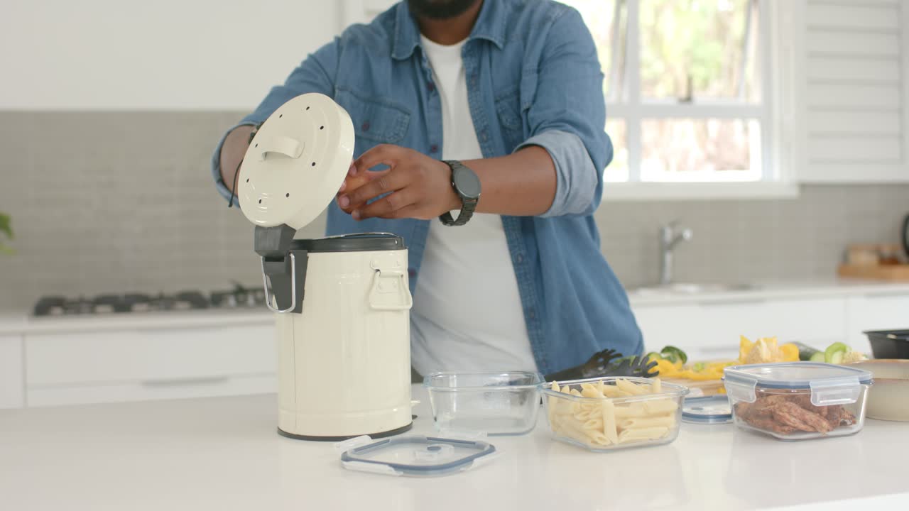 Uomo afroamericano che solleva un coperchio e rompe un uovo in un elettrodomestico color crema sul bancone, mentre prepara la colazione