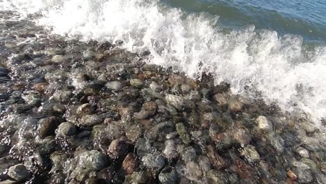 Close-up-shot-of-waves-coming-in-and-out-on-rock-beach-in-Batumi-Georgia