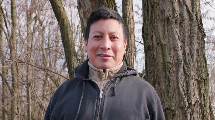 Ritratto di un uomo ecuadoriano con il sole sul viso che sorride nella foresta durante un pomeriggio invernale - inquadratura media, rallentatore.