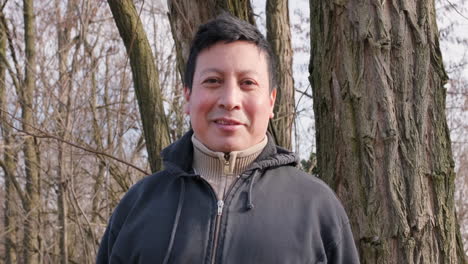 portrait of an ecuadorian man with the sun on his face smiling in the forest during a winter afternoon - medium shot, slow motion