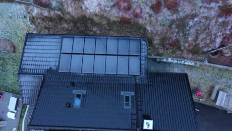 frozen solar panels with zero electricity production during dark winter season - upward moving top-down aerial of private home in norway