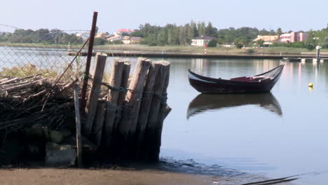 a boat moored in the river, with wooden stakes holding up one of the banks