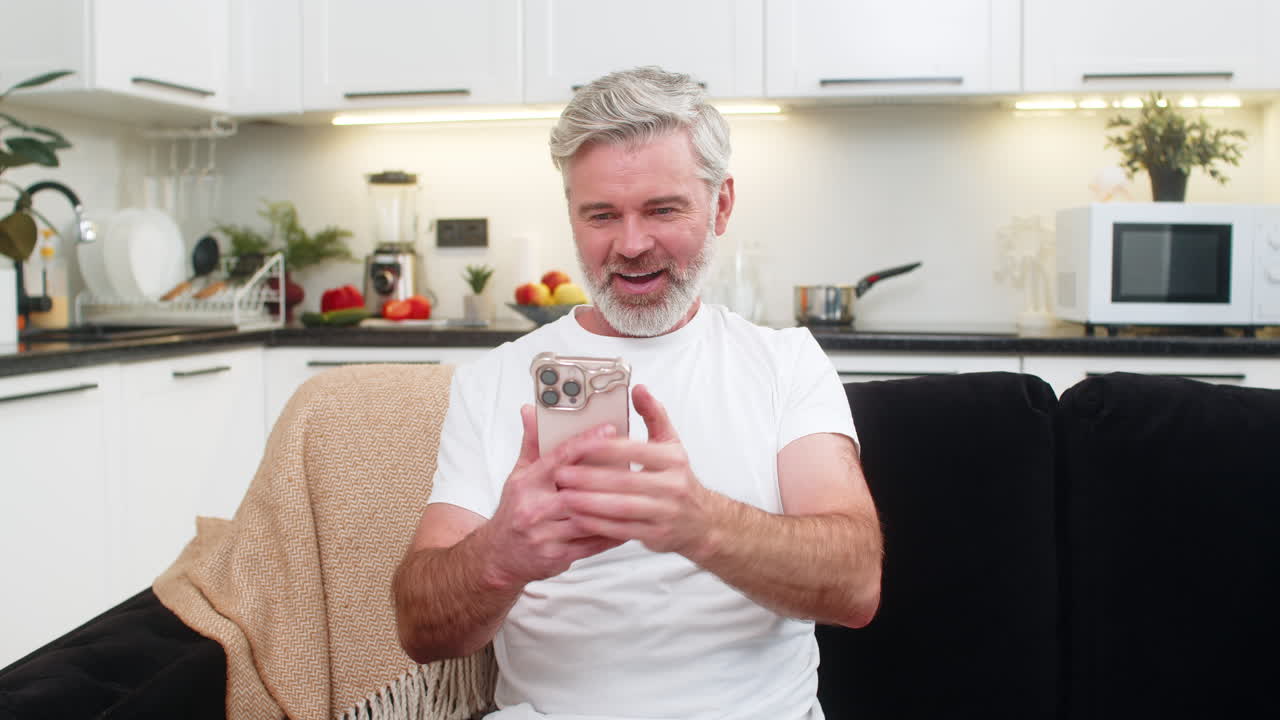 Middleaged man celebrates good news on smartphone laughs with joy after online game big win success