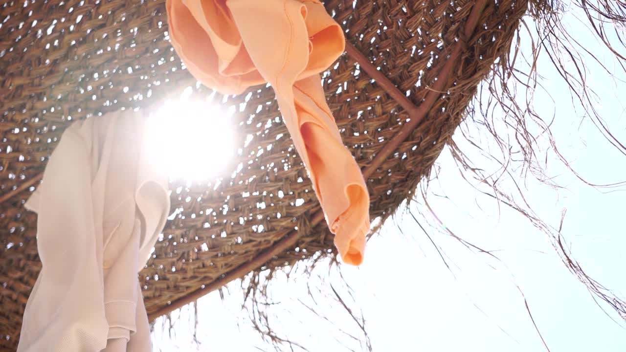Sun rays and breeze passing beach umbrella with clothes flying. 2
