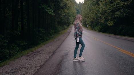 profile shot of a pretty caucasian woman crossing a road surrounded by woodlands in vancouver