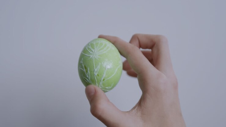 Hand holding a decorated green easter egg