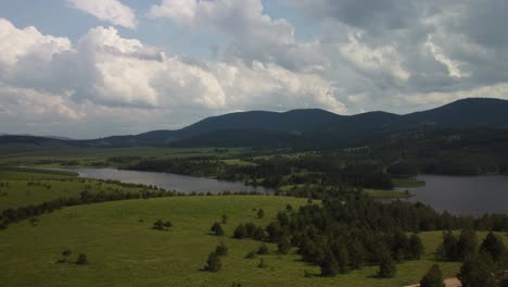 Serene-landscape-with-rolling-green-hills,-a-tranquil-lake,-and-a-partly-cloudy-sky