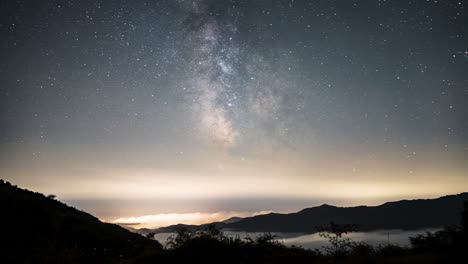 stars twinkle over misty mountains under the milky way in a serene night sky timelapse