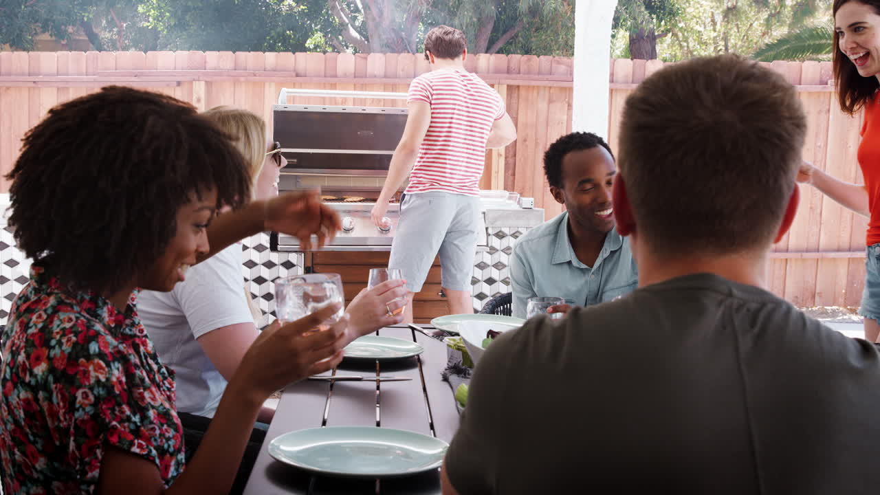 Amigos jóvenes sentados al aire libre haciendo una barbacoa