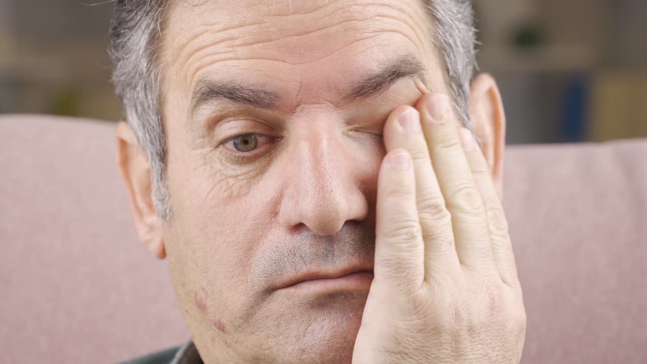 un hombre maduro con discapacidad visual se quita las gafas y ve borroso.