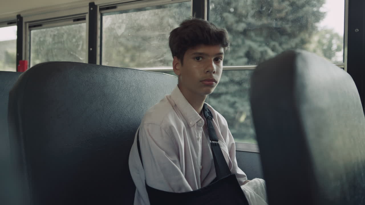 인도 학생은 슬프게도 가까이 카메라를 보고 있습니다. 십대 소년은 학교 버스에 앉아 있습니다.