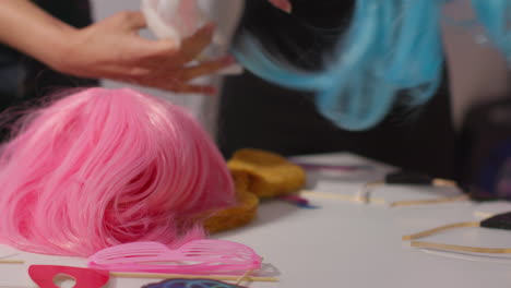 close up of wigs and props outside photo booth with people in background