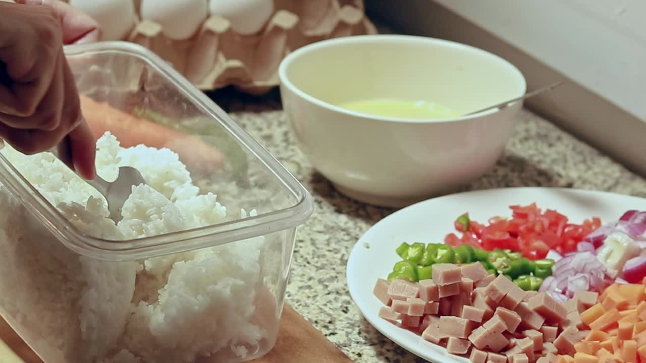 Breaking up clumps of leftover rice, preparing the ingredients for a healthy vegetarian fried rice recipe. Healthy home living