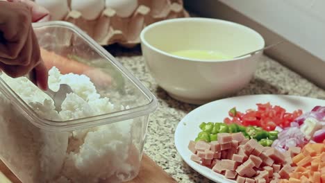 breaking up clumps of leftover rice, preparing the ingredients for a healthy vegetarian fried rice recipe. healthy home living